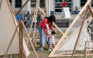 Adult and baby walking through wooden tent-scape